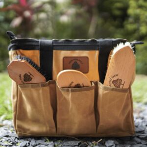 Tan SP Rhodes grooming tote with a Pear Tree Farm leather patch, holding engraved wooden brushes, photographed outdoors